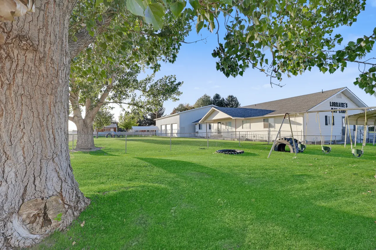 Lush lawn and giant shade trees on the 1-acre campus at Lorraines Daycare in Burley